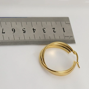 Vista detallada de pendientes de aro dorados de 40mm junto a una regla de acero graduada
