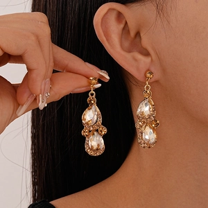 Detailed view of champagne teardrop earrings in vintage gold setting with pavé diamonds