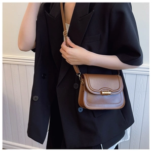 Gros plan d'un sac bandoulière en cuir marron avec boucle dorée et bandoulière réglable