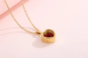 Macro detail of gold heart pendant necklace featuring a vibrant red gemstone inlay