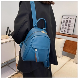 Close-up of royal blue pebble leather backpack featuring gold zippers and buckle details