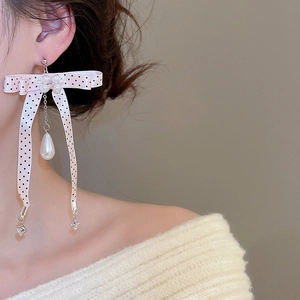 Detail shot of a pink polka dot ribbon bow earring with hanging pearls and zircon charms