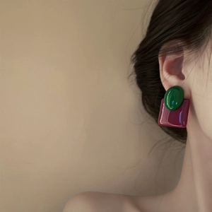 Close-up of retro oval earrings with green and burgundy contrast color block design