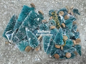 Close-up of mini turquoise Christmas trees with snow tips and wooden base in polybag