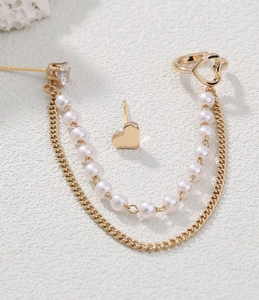 Detail of gold heart earrings set with pearl tassels and crystal studs for women