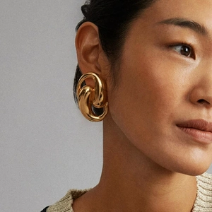 Polished 18K gold-plated stainless steel teardrop hoop earrings on a model