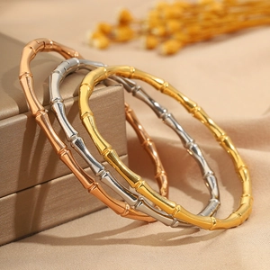 Bracciali stile bambù in acciaio al titanio oro, argento e oro rosa impilati con cura
