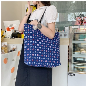 Detail of blue canvas tote bag with nautical anchor print and thick white rope handles