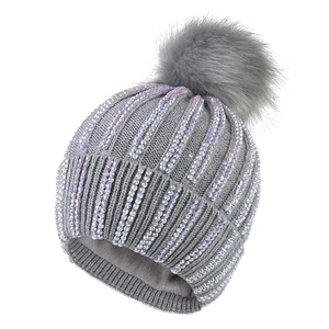 Detail of grey knitted beanie with colorful gradient rhinestones and faux fur pompom