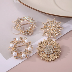 Détail de quatre broches dorées élégantes avec des strass brillants et des perles