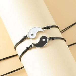 Adjustable Yin Yang braided bracelets for friends in black and white on a display stand