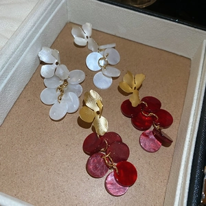 Detail view of red and white acrylic flower earrings in a gift box with golden metal pins