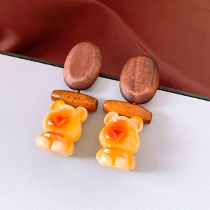 Detailed close-up of vintage wooden bear earrings with translucent amber resin pendants