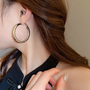 Close-up of a silver-toned metal large hoop earring worn by a model in a modern style