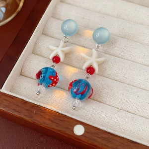 Detail of starfish pendant earrings with colorful glass beads in a velvet jewelry box
