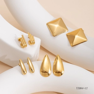 Macro view of four pairs of polished gold-plated hoop earrings with unique geometric textures