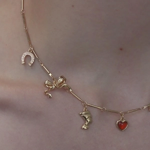 Close-up of golden titanium necklace featuring butterfly and red heart gemstone pendants