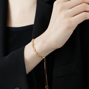 Close-up of golden adjustable bracelet with zircon flower detail on model's wrist
