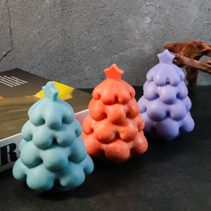 Three colorful Christmas tree candles in blue, pink, and purple with star toppers
