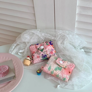 Close-up of quilted floral coin purse with cute cupcake charms on lace background