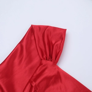 Macro shot of elegant red satin evening dress featuring pleated off-shoulder sleeve details