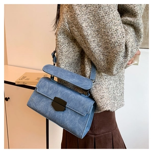 Detail of blue denim shoulder bag with magnetic metal clasp and long top handle