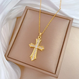 Close-up of gold cross pendant with clear zircons in a champagne jewelry box with silk