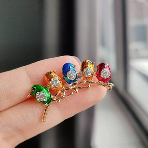 Close-up of five colorful enamel birds brooch with sparkling rhinestones on golden branch