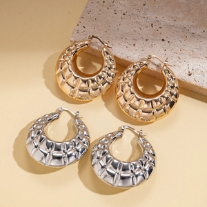 Chunky textured geometric hoop earrings in gold and silver finish on stone display