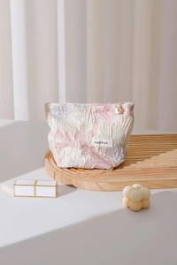 Macro detail of textured floral jacquard fabric and golden flower zipper pull on makeup bag