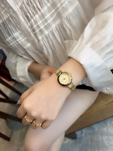 Detail of octagonal gold ladies watch with brand logo on wrist in soft lighting