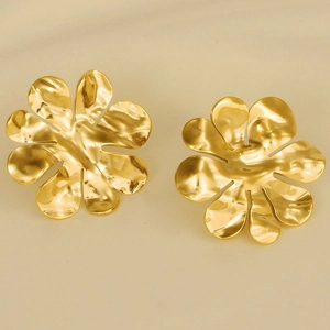 Detail shot of 18k gold plated flower stud earrings with a matte texture on beige surface