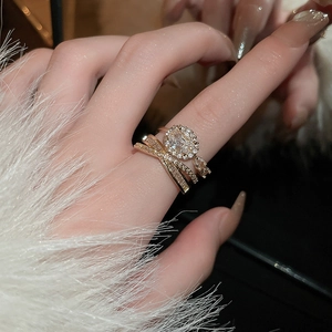 Dettaglio di un anello multistrato placcato oro con zircone ovale e pietre pavé sulla mano