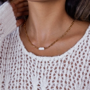 Detail van paperclip ketting met natuurlijke barokparel gedragen door een model
