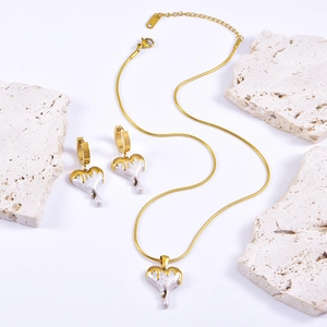 Minimalist gold and white melting heart necklace and earrings set on stone decor
