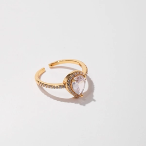 Close-up of a pear-cut white zircon ring with halo setting on a gold open band
