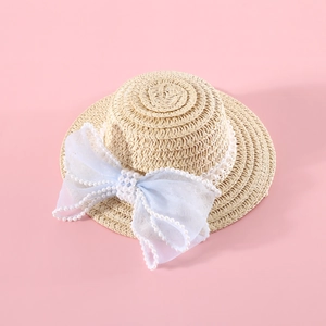 Detail of woven pet straw hat with blue lace bow and decorative white pearls