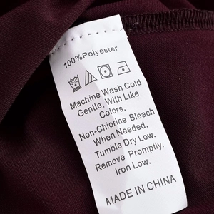 Detailed close-up of 100% polyester fabric care label with washing instructions and icons