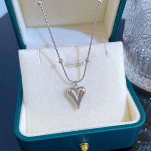 Macro view of silver puffed heart pendant with bead chain on elegant jewelry box