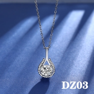 Close-up of teardrop moissanite pendant with halo setting on a dark textured background
