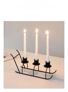 Detail of a matte black metal sleigh candle holder with three white spiral candles