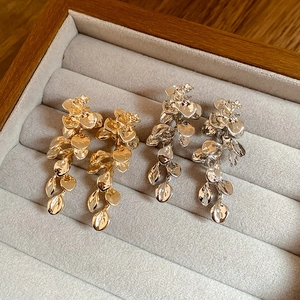 Macro shot of leaf-shaped tassel earrings in gold and silver finish on velvet