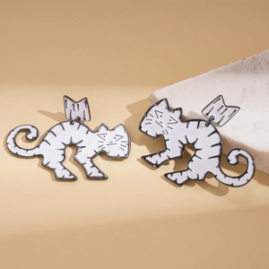 Close-up of white enamel winged cat earrings with black outlines on stone base