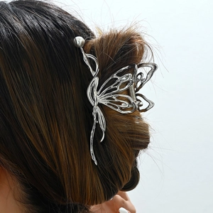 Elegant silver butterfly metal hair claw with pearl detail worn by model on white background