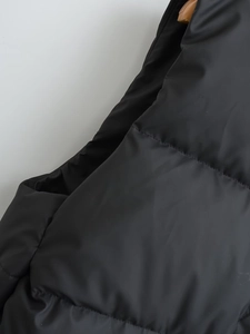 Close-up of black padded vest showing quality stitching and satin finish fabric detail