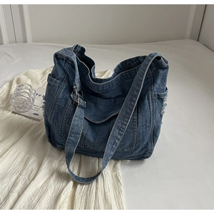 Détail du sac cabas en denim avec bords effilochés et boucle métallique argentée ajustable