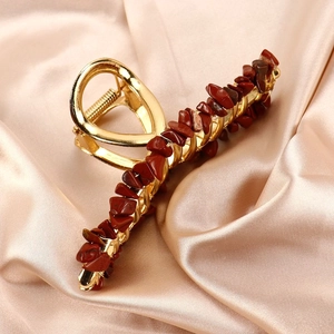 Close-up of golden alloy hair claw clip inlaid with natural red jasper stones