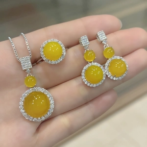 Detailed view of yellow chalcedony jewelry set with necklace ring and earrings on palm