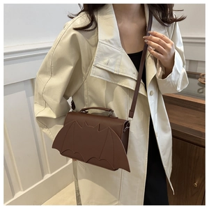 Detailed view of dark brown bat-winged crossbody bag worn with a white coat