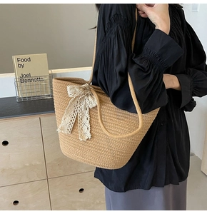Close-up of handwoven straw tote bag featuring a creamy white lace bow detail
